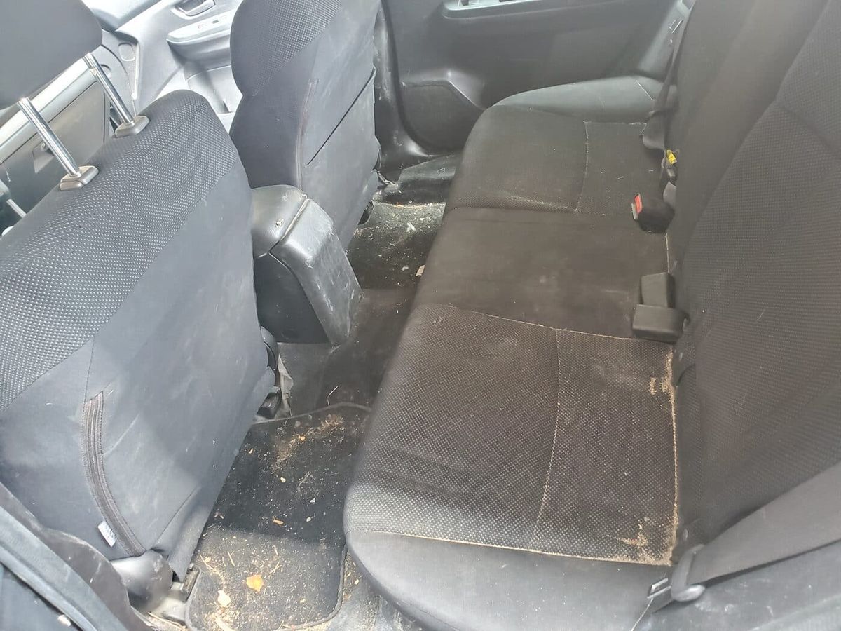 Dirty rear cloth seats with stains and debris before interior detailing